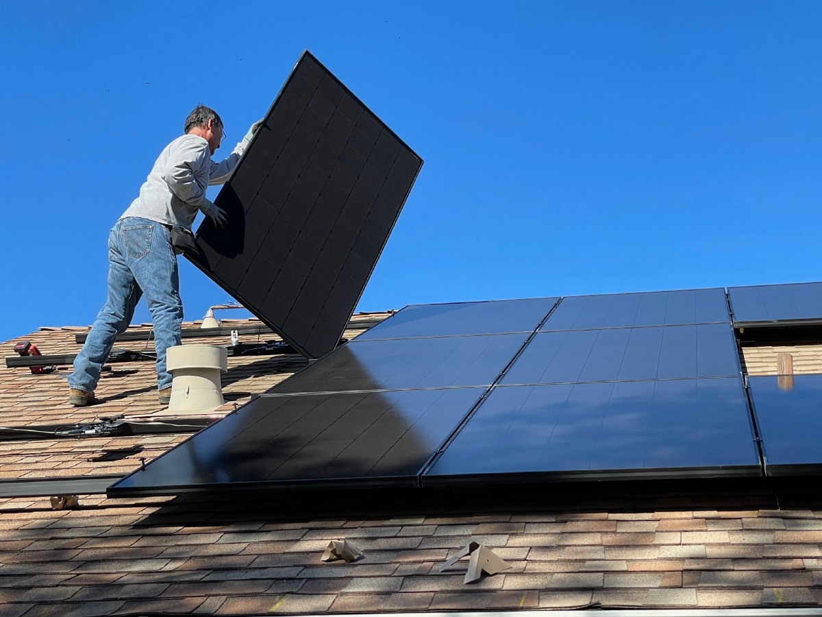 A person putting a solar panel on a rooftop